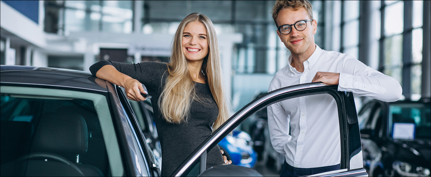 store front two people smiling beside the car