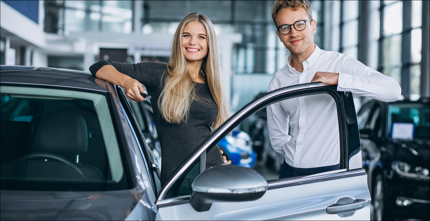 store front two people smiling beside the car
